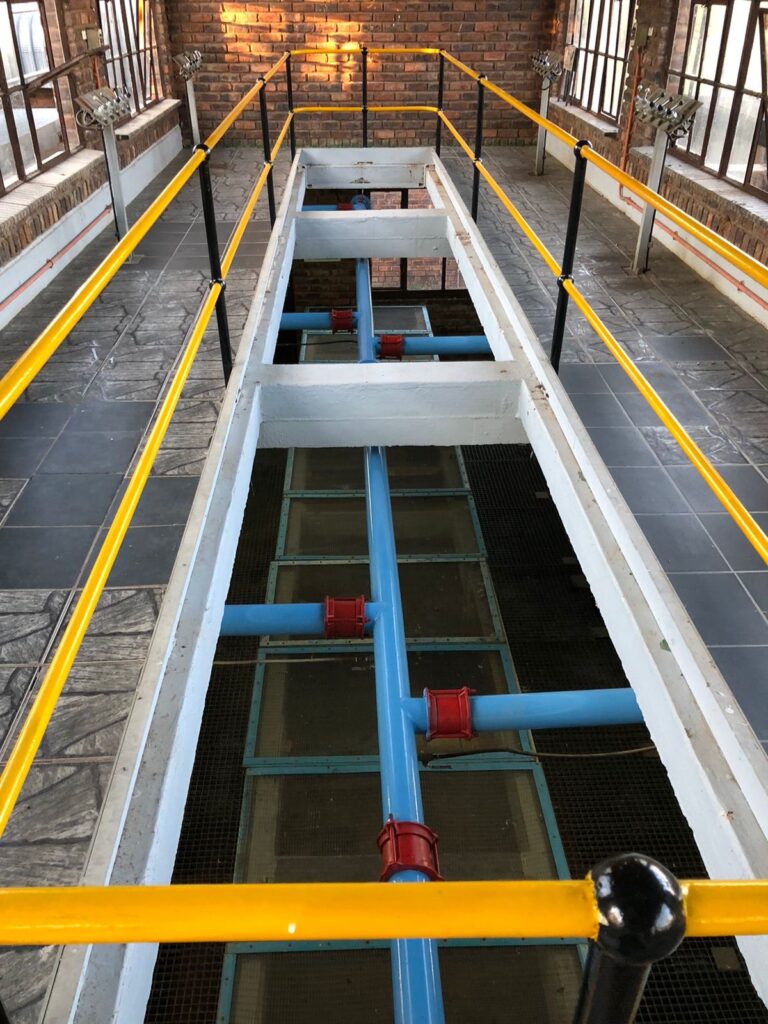 Industrial plant platform with safety rails and pipework