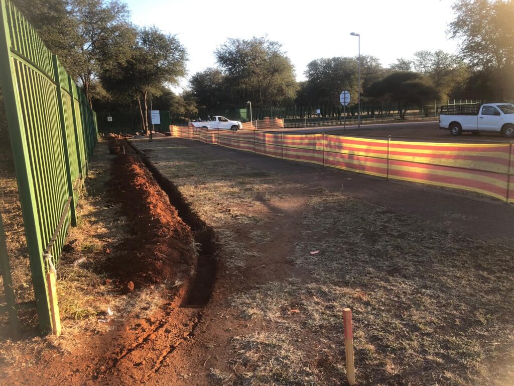 Underground service trench beside a property fence