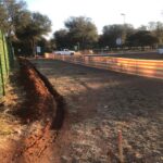 Underground service trench beside a property fence